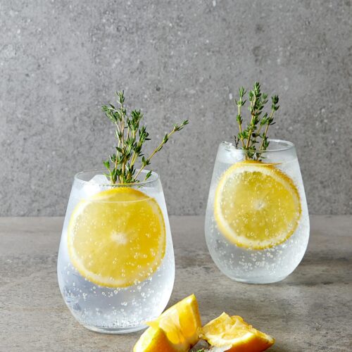 2 Gin Tonics garnished with orange and rosemary